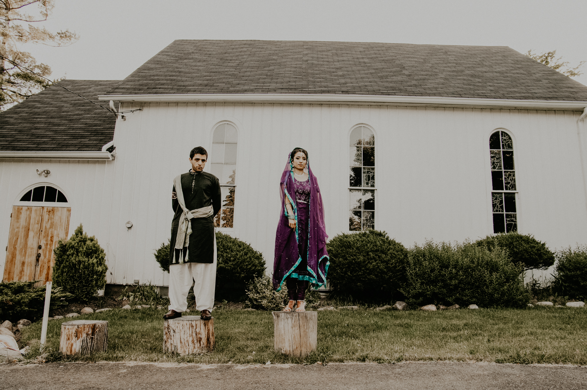 Bride and groom stand on logs outside temple at Indian wedding ceremony
