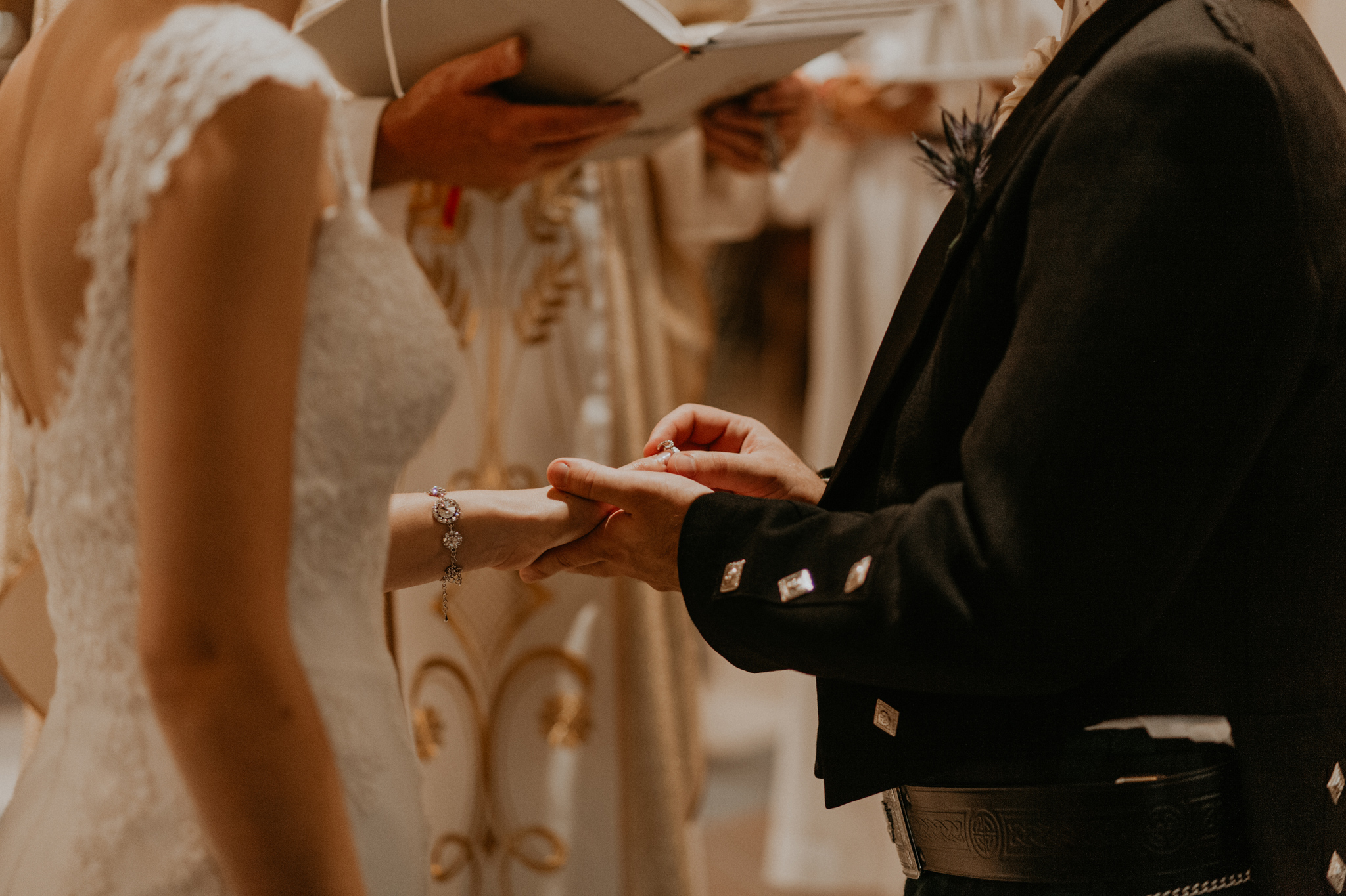 Groom smiling while placing ring on bride's finger