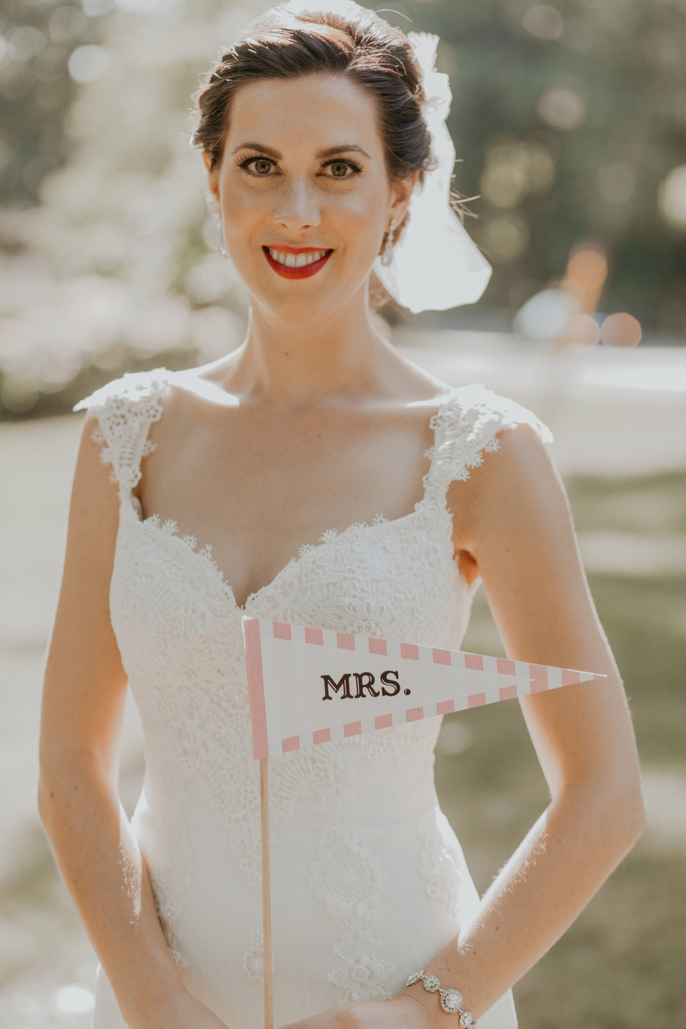 Portrait of bride on wedding day holding "Mrs" flag