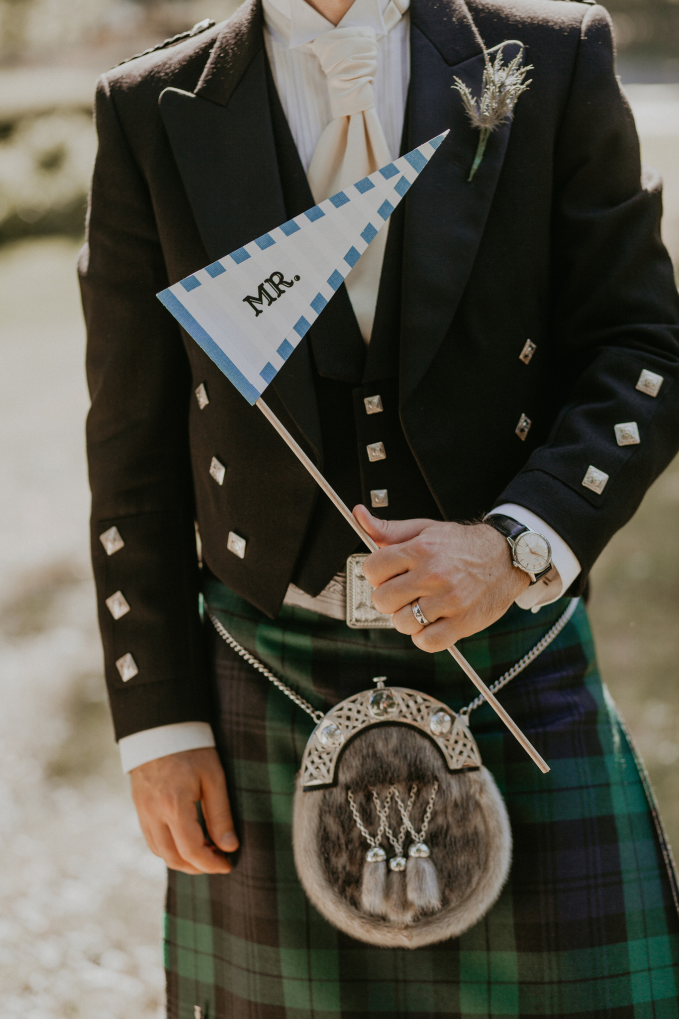 Close up of groom on wedding day holding "Mr." flag