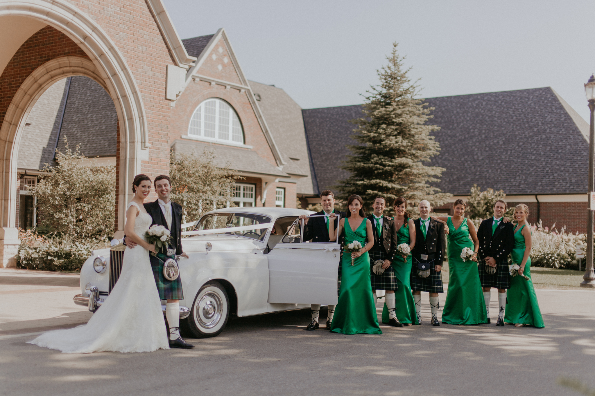 Wedding party pose in kilts and green bridesmaid's dresses with Rolls Royce