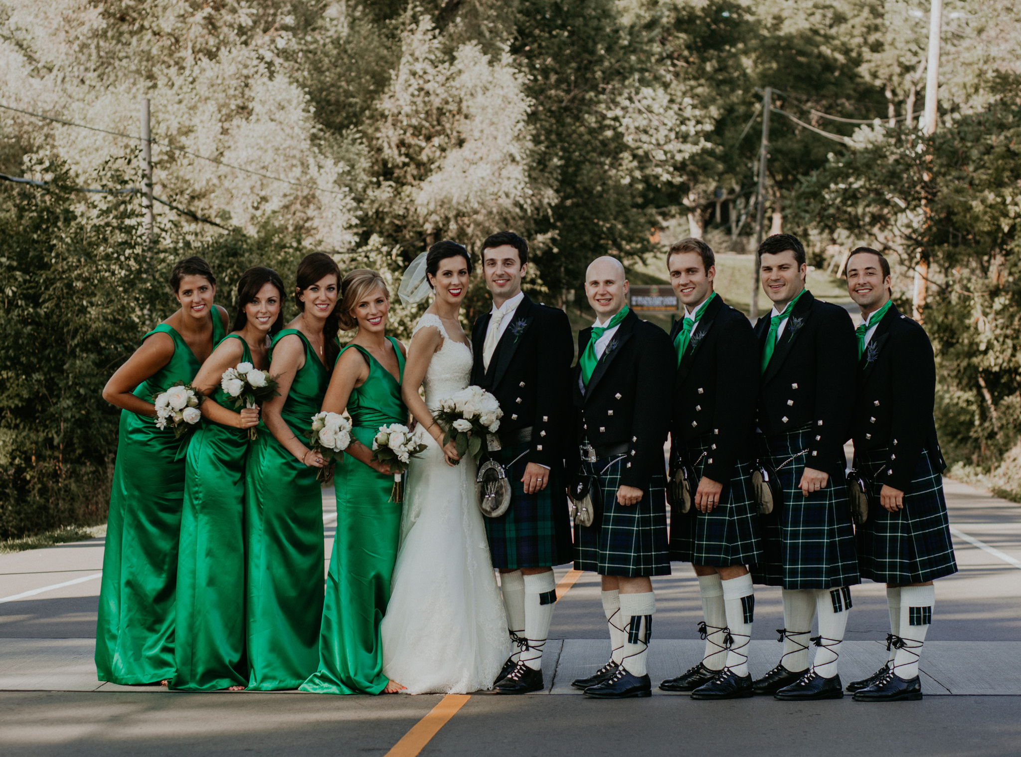 portrait of wedding party in kilts and green dresses posing in street