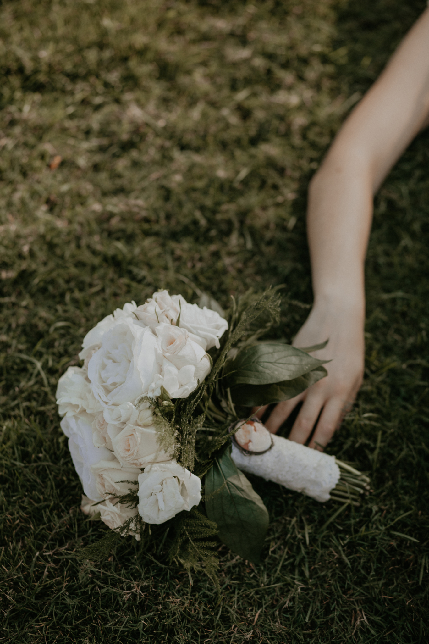 Bride lays down in grass holding bouquet