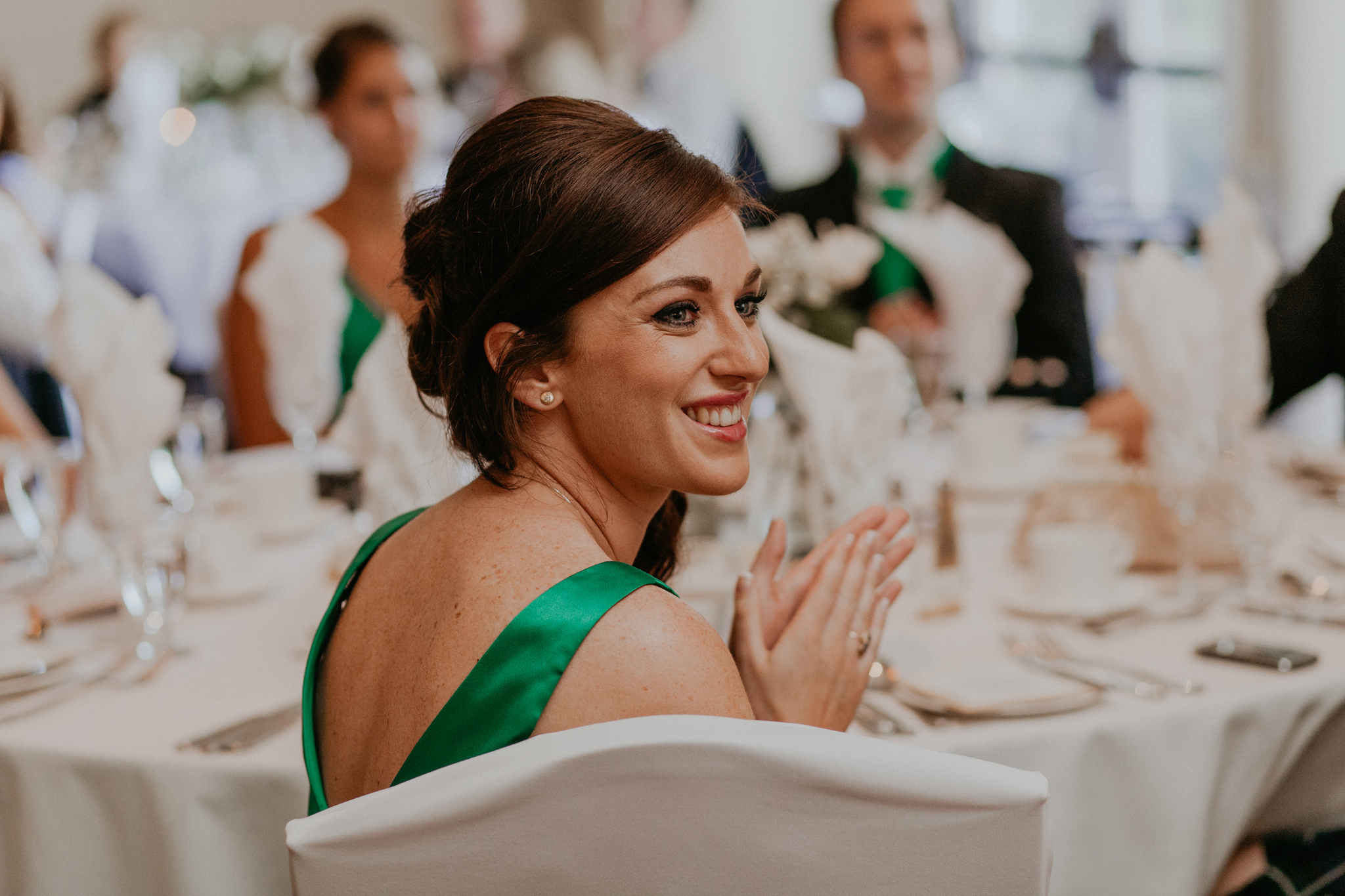 Bridesmaid in green dress smiles during reception documentary wedding photo