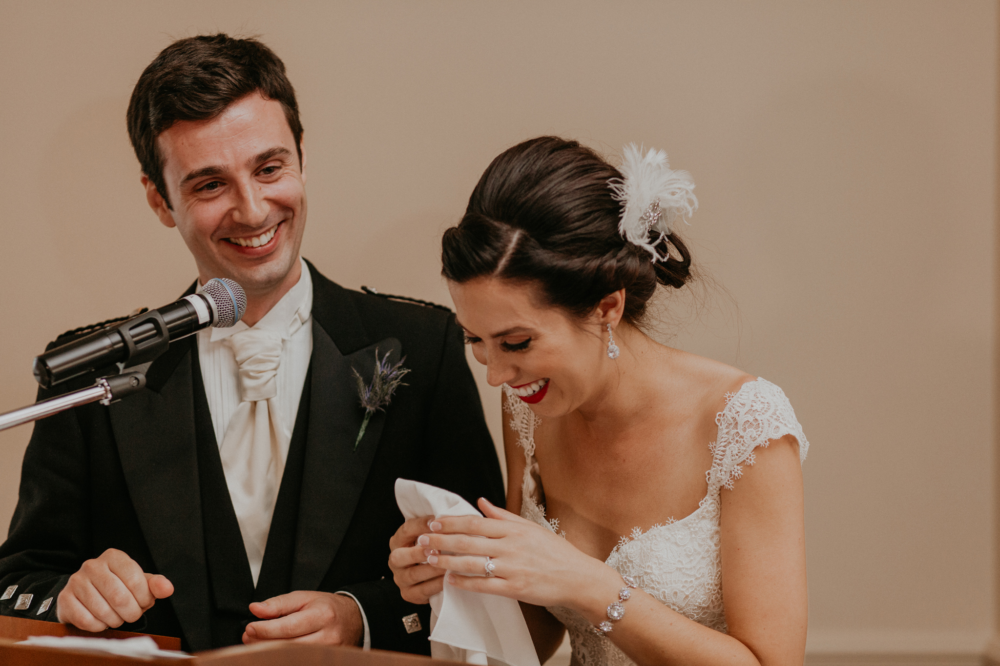 Bride and groom laugh in candid photo during speech