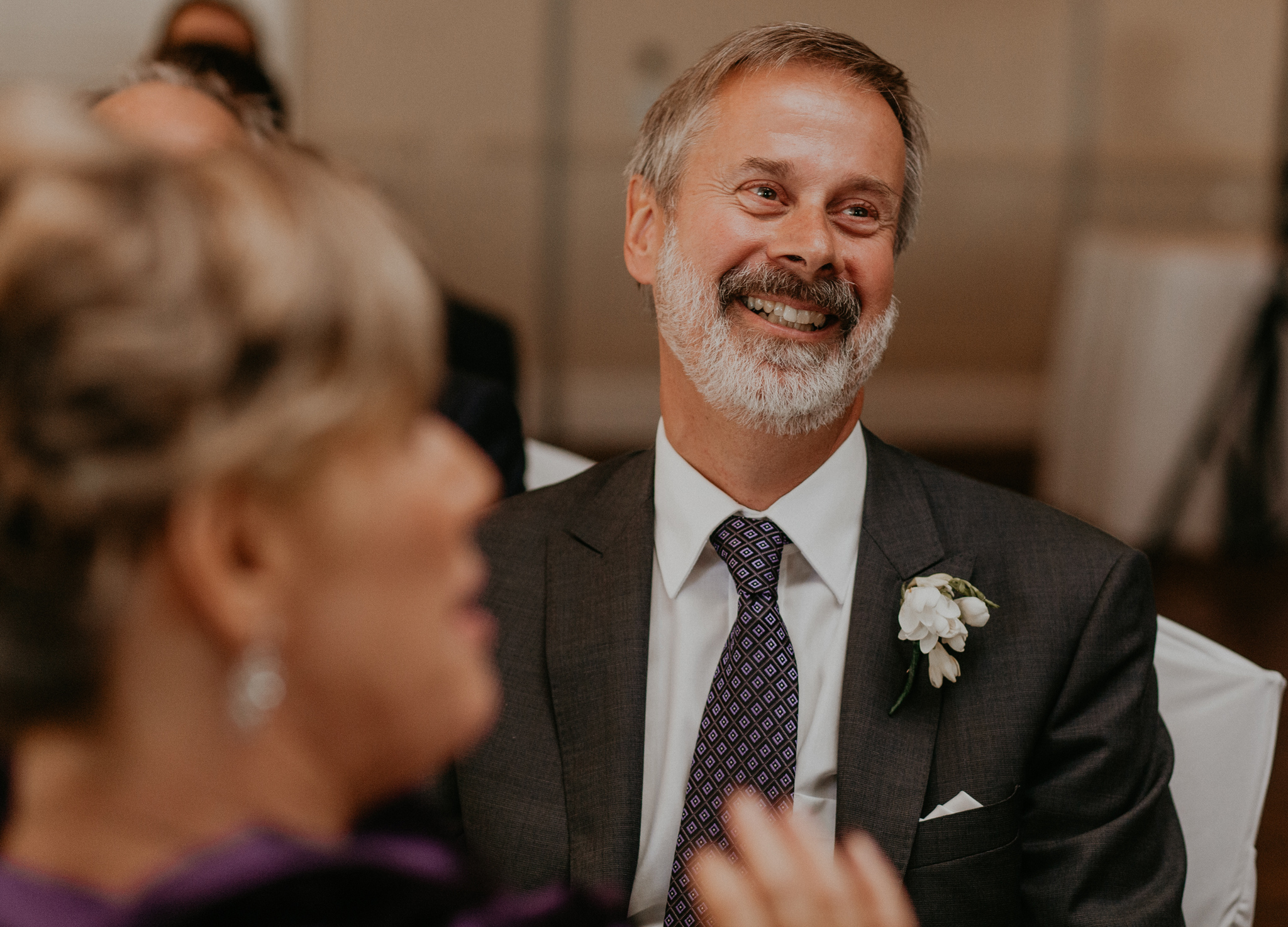 Father laughs during wedding reception for bride and groom in candid photo