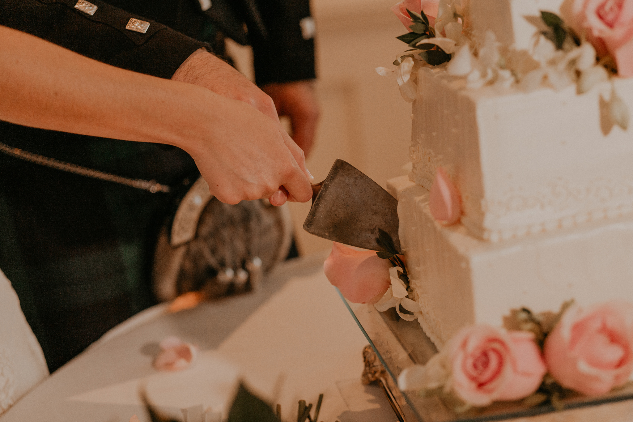 Close up photo of bride and groom cutting wedding cake