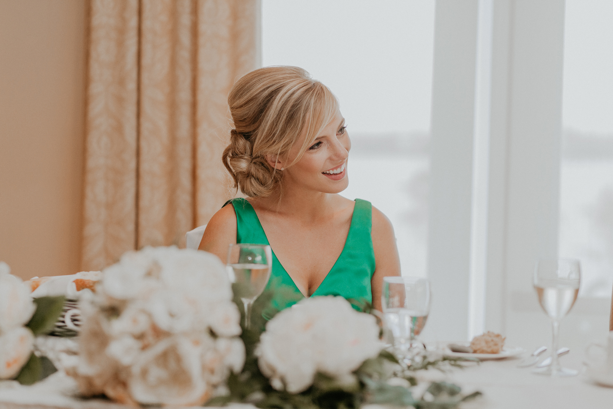Maid of honor smiles at head table in wedding reception