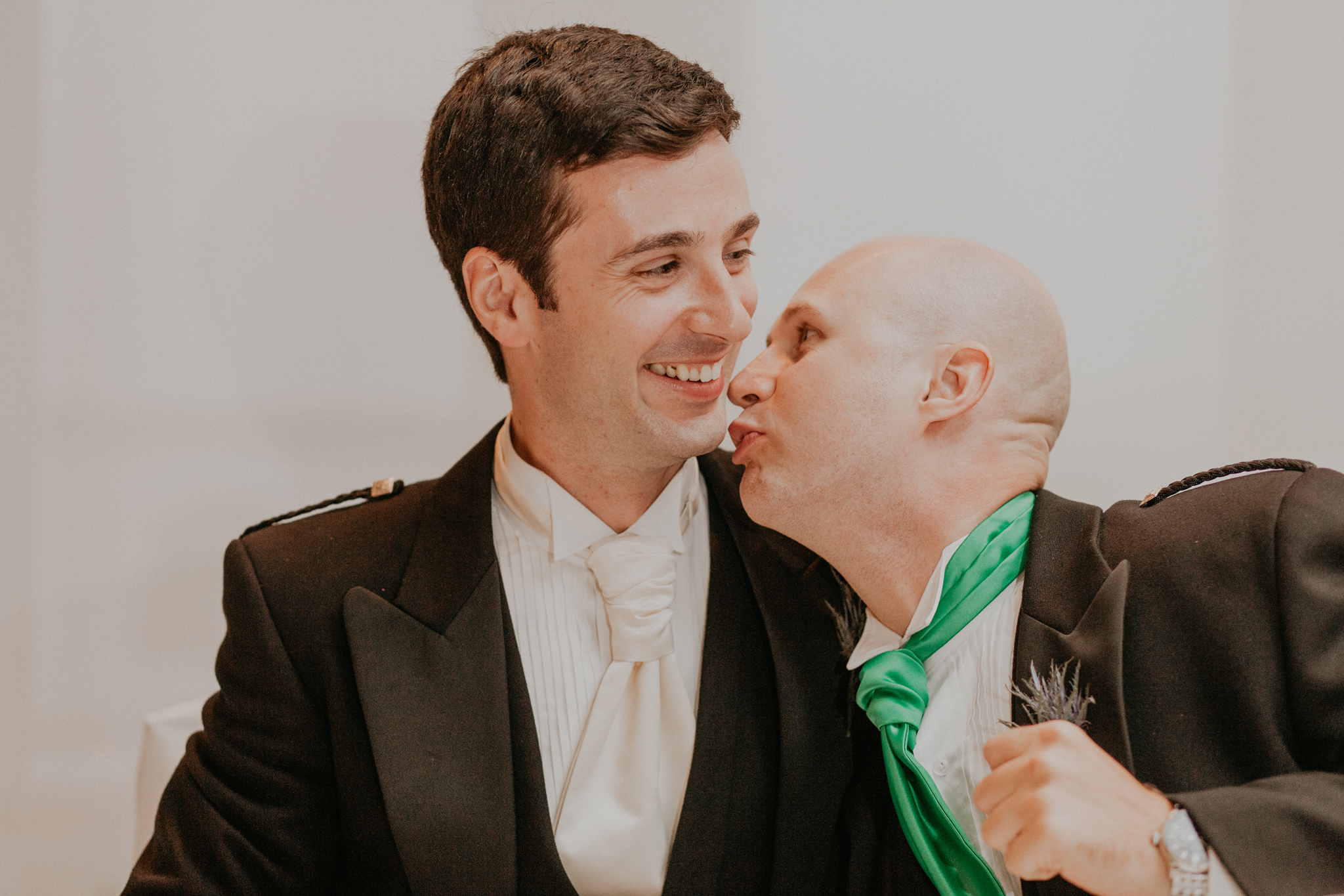 Groomsmen jokes and kisses groom during wedding reception 