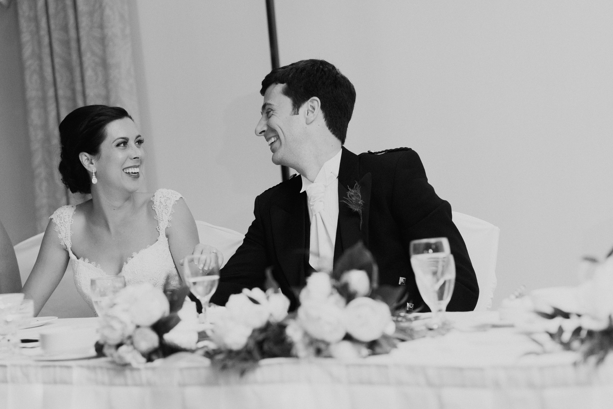 Black and white documentary photo of Bride and Groom laughing during speeches