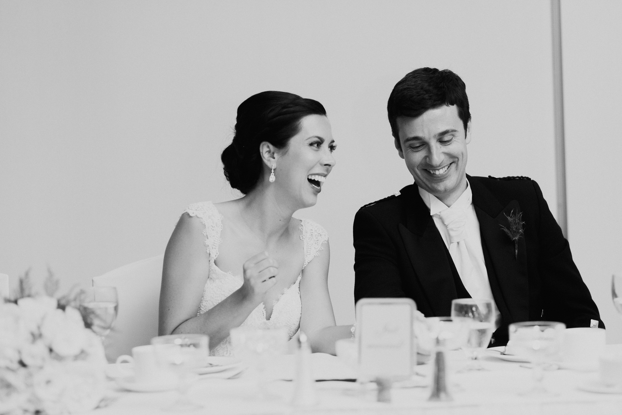 Black and white documentary photo of Bride and Groom laughing during speeches