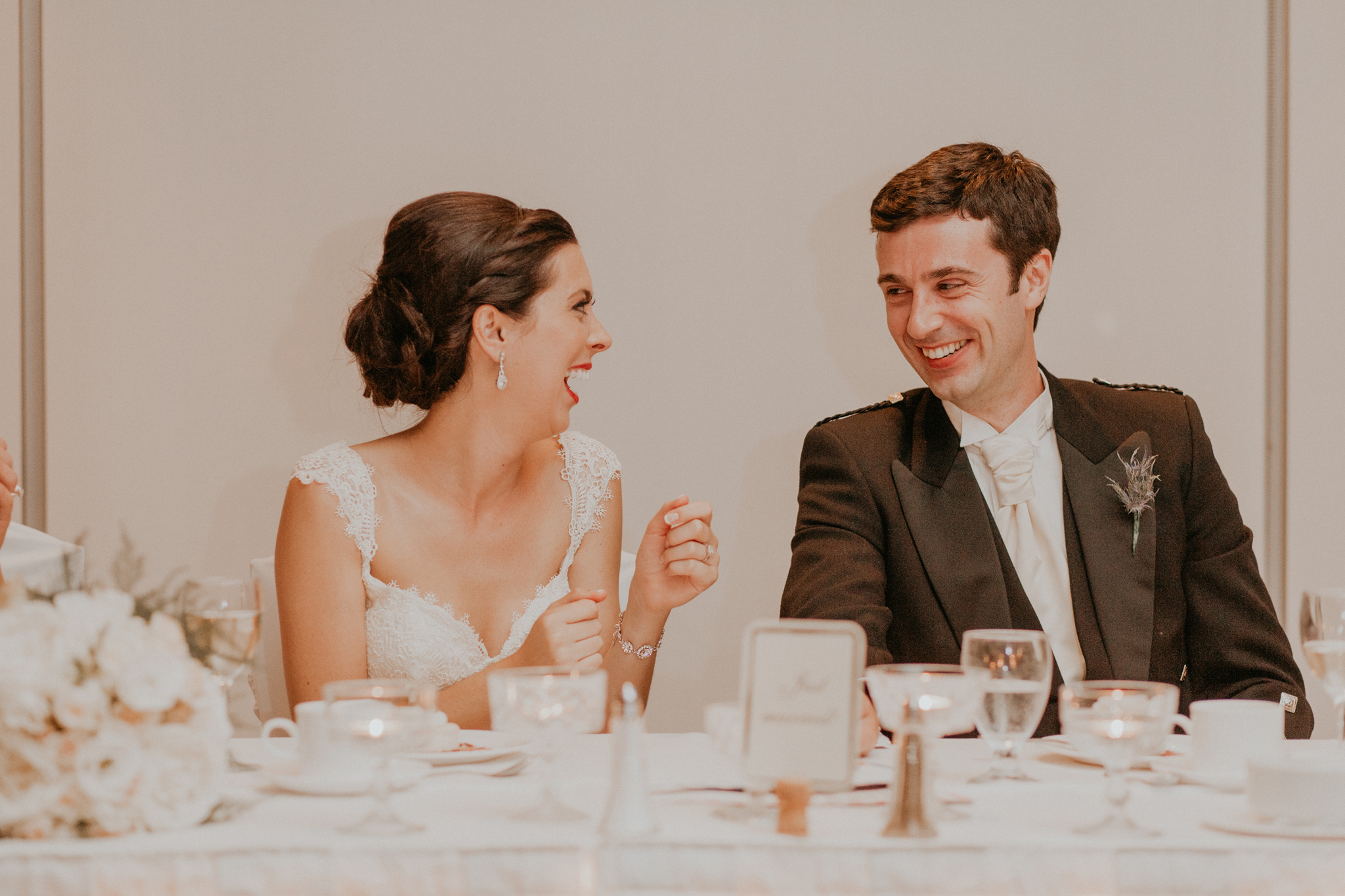 Candid documentary photo of bride and groom laughing during speech