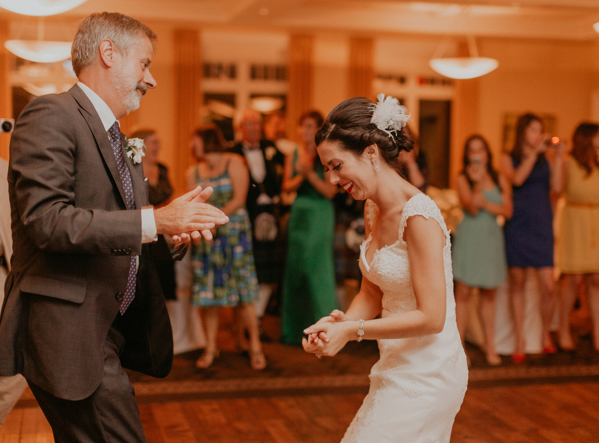 Bride smiles and has fun dancing with father during wedding