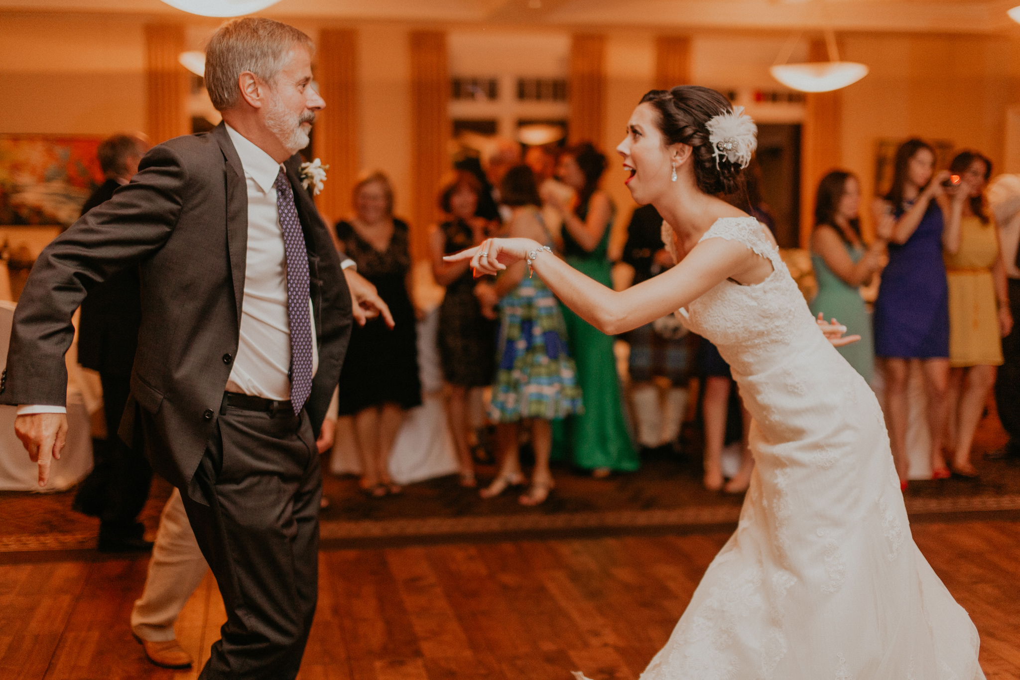 Bride smiles and has fun dancing with dad during wedding