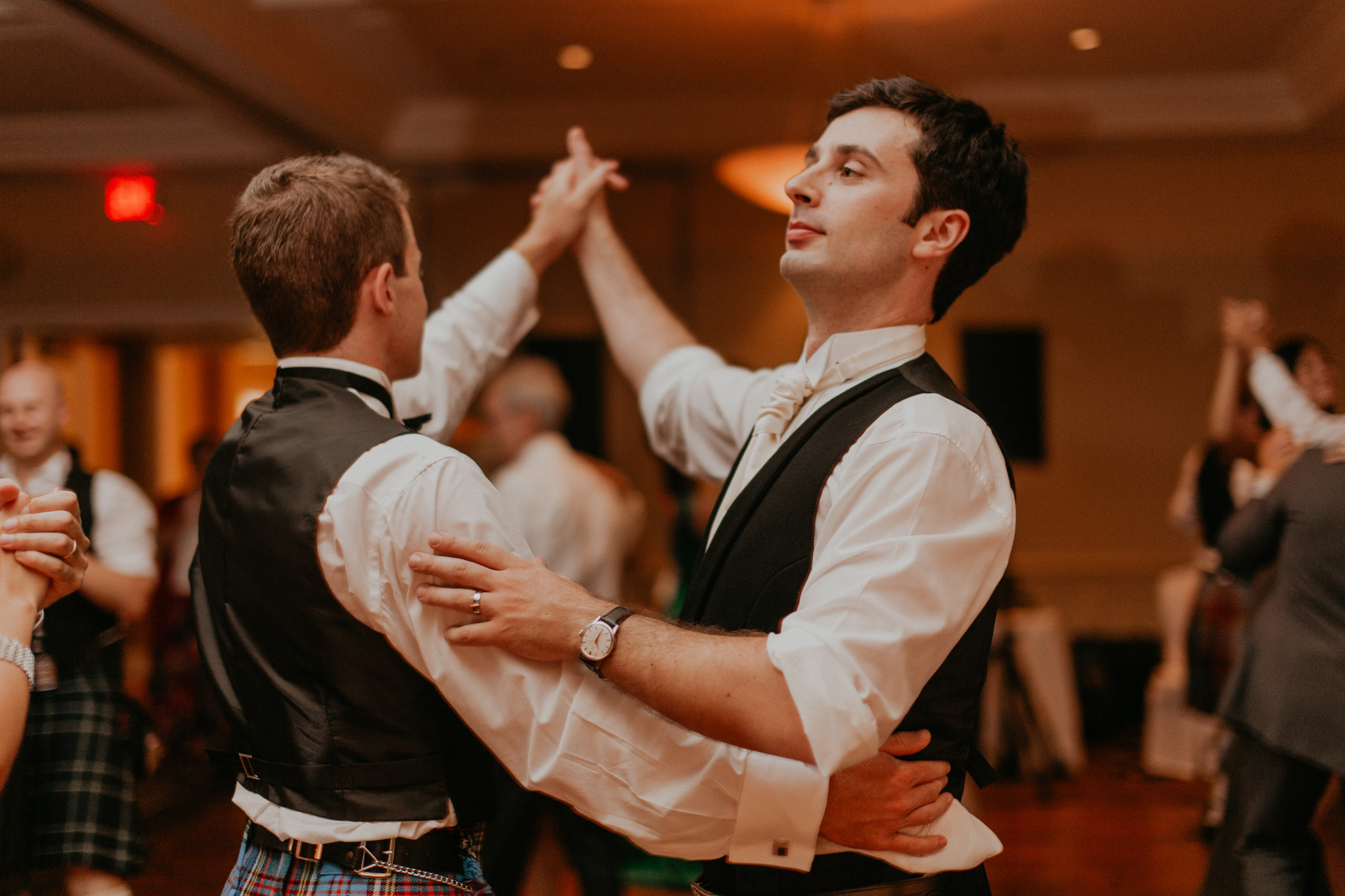 Groom and groomsmen dance in kilts at wedding reception candid documentary photography