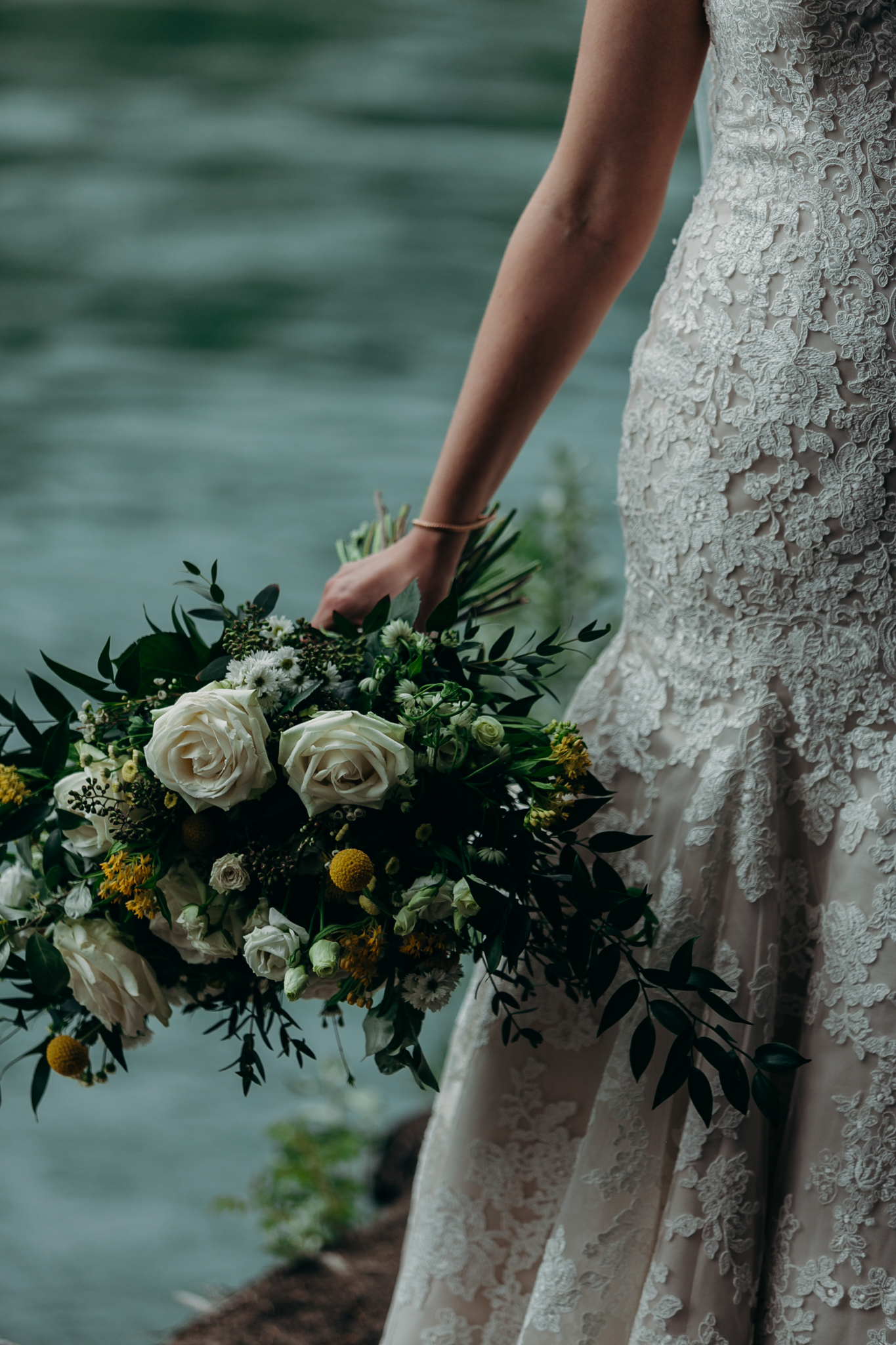 Close up of bride's bouquet and hand holding bouquet with Bow River in background