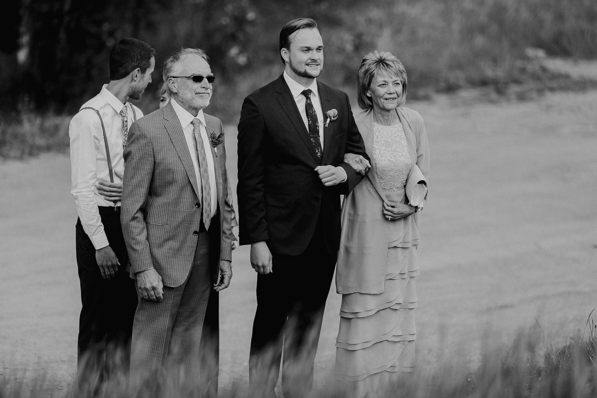 Black and white photo of groom walking aisle with mom and dad Silvertip Resort Canmore AB