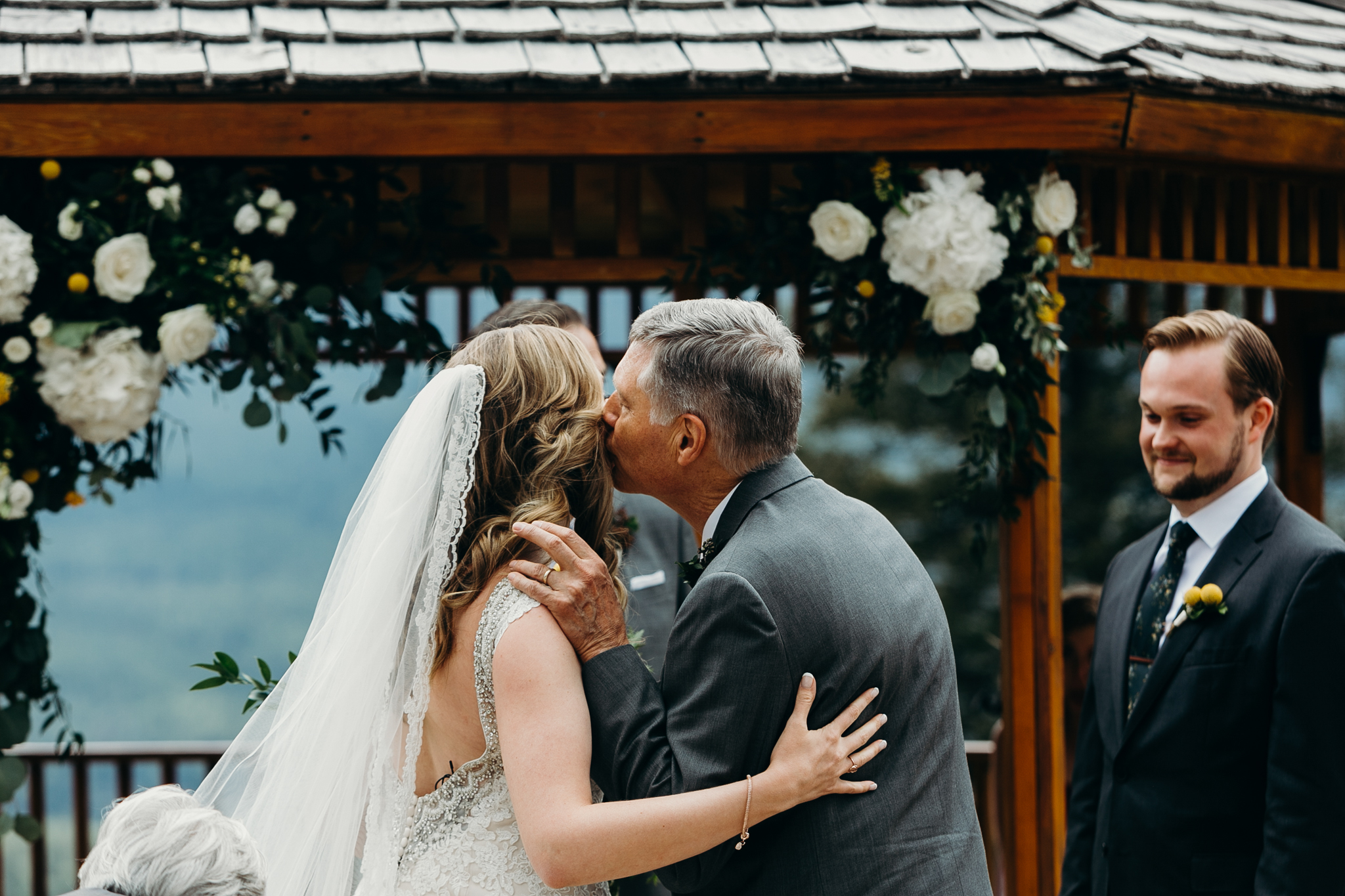 Father kisses Bride's cheek at Silvertip Resort's gazebo wedding ceremony Canmore AB