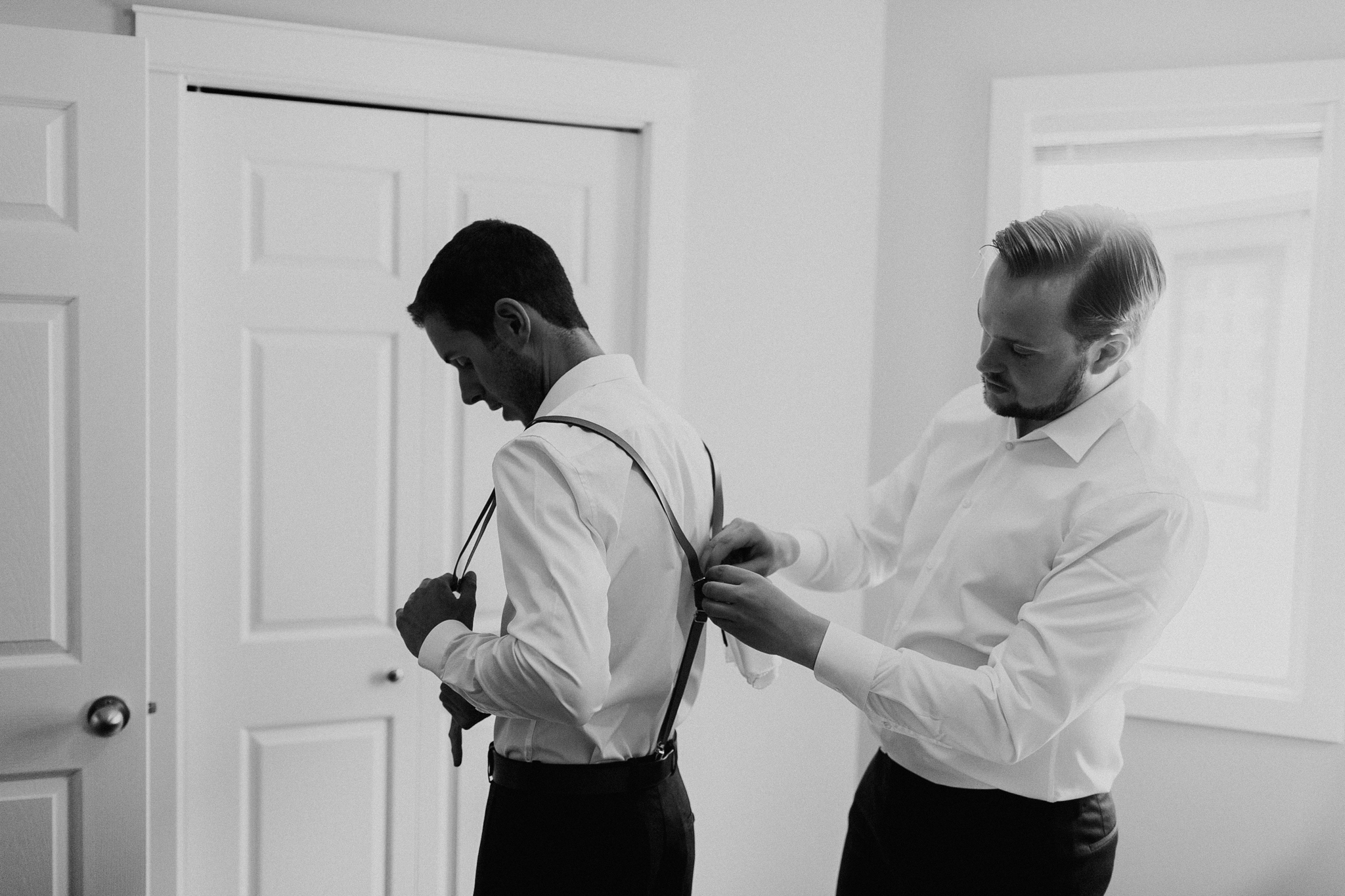 Groom helping best man put on suspenders documentary wedding photographer