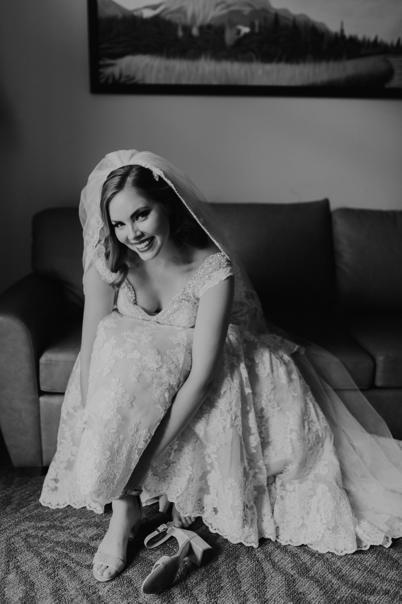 Bride sitting on couch putting on shoes at destination wedding in Canmore Alberta