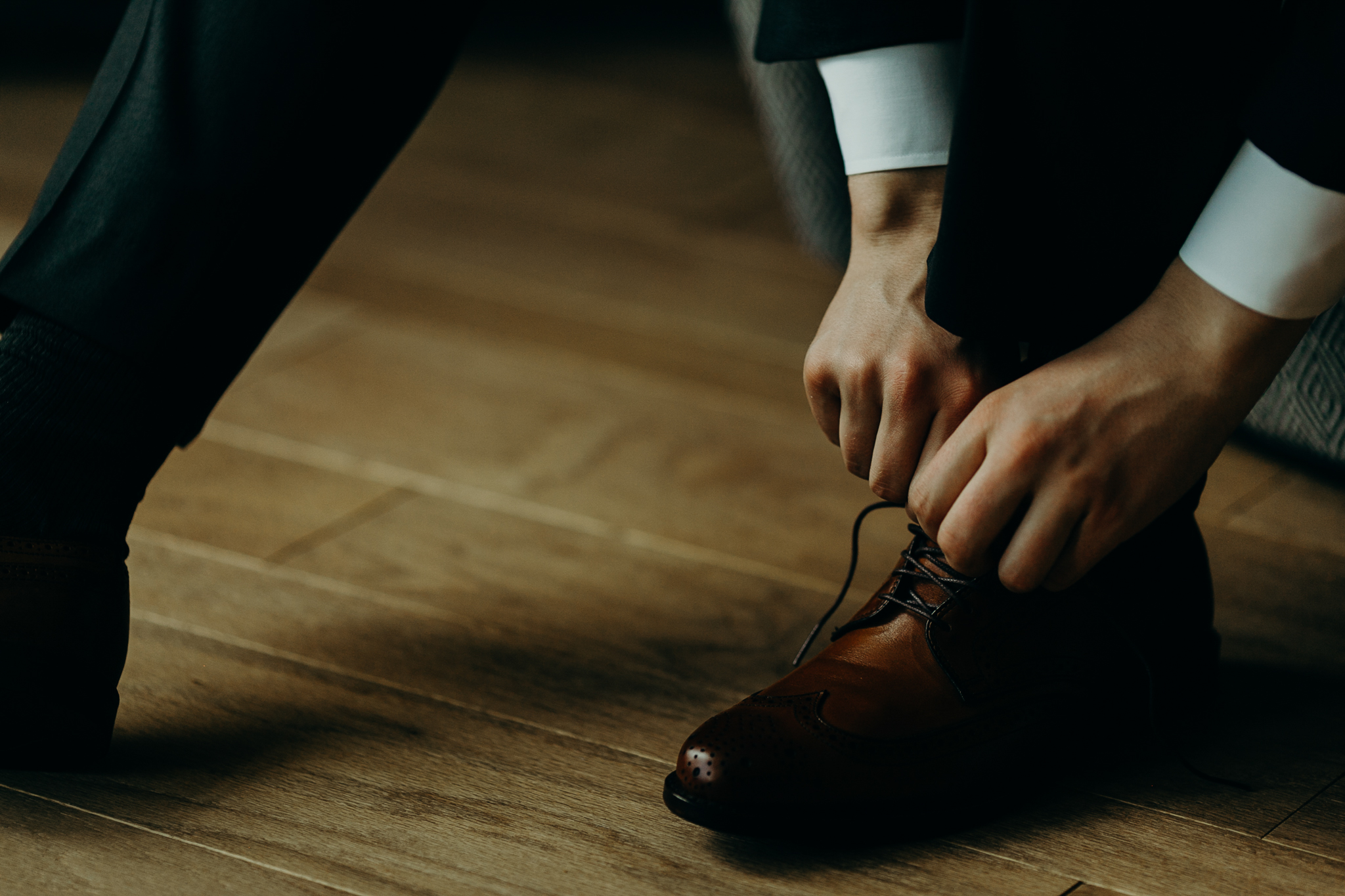 Close up of hands tying brown dress shoes