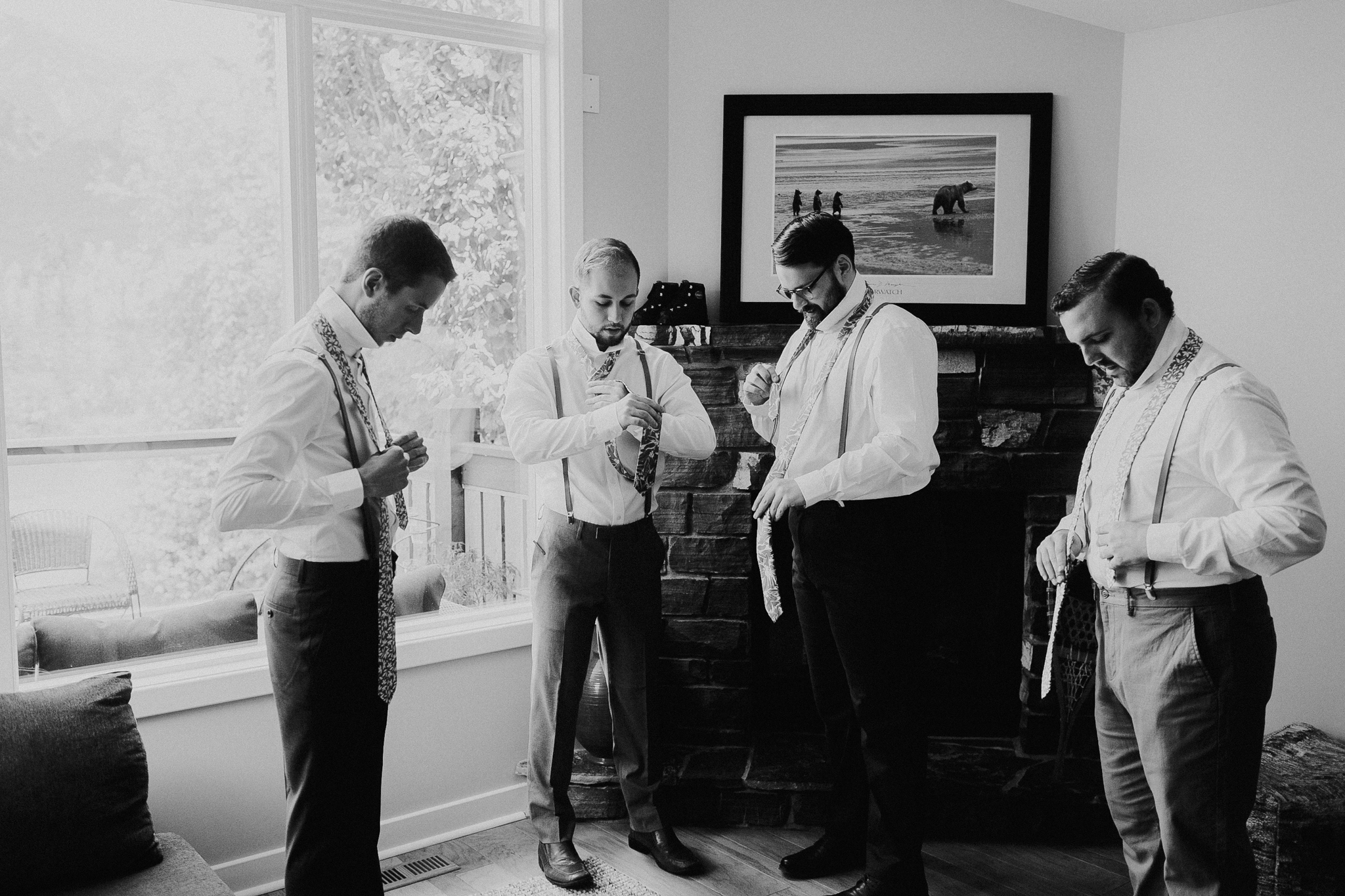 Documentary wedding photo of four groomsmen in black and white getting ready