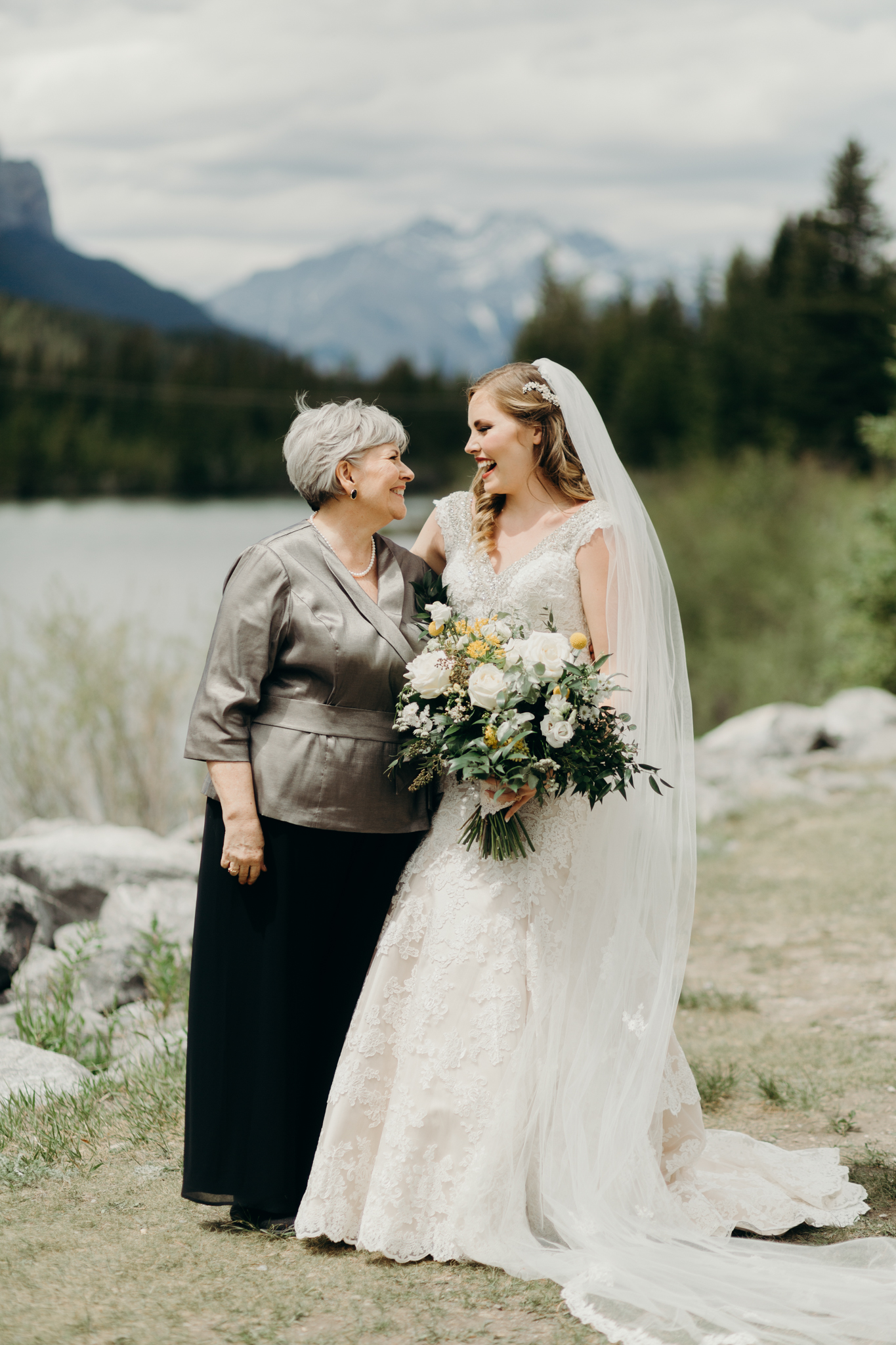Bride and Mother of bride pose by river smiling destination wedding photographer MN