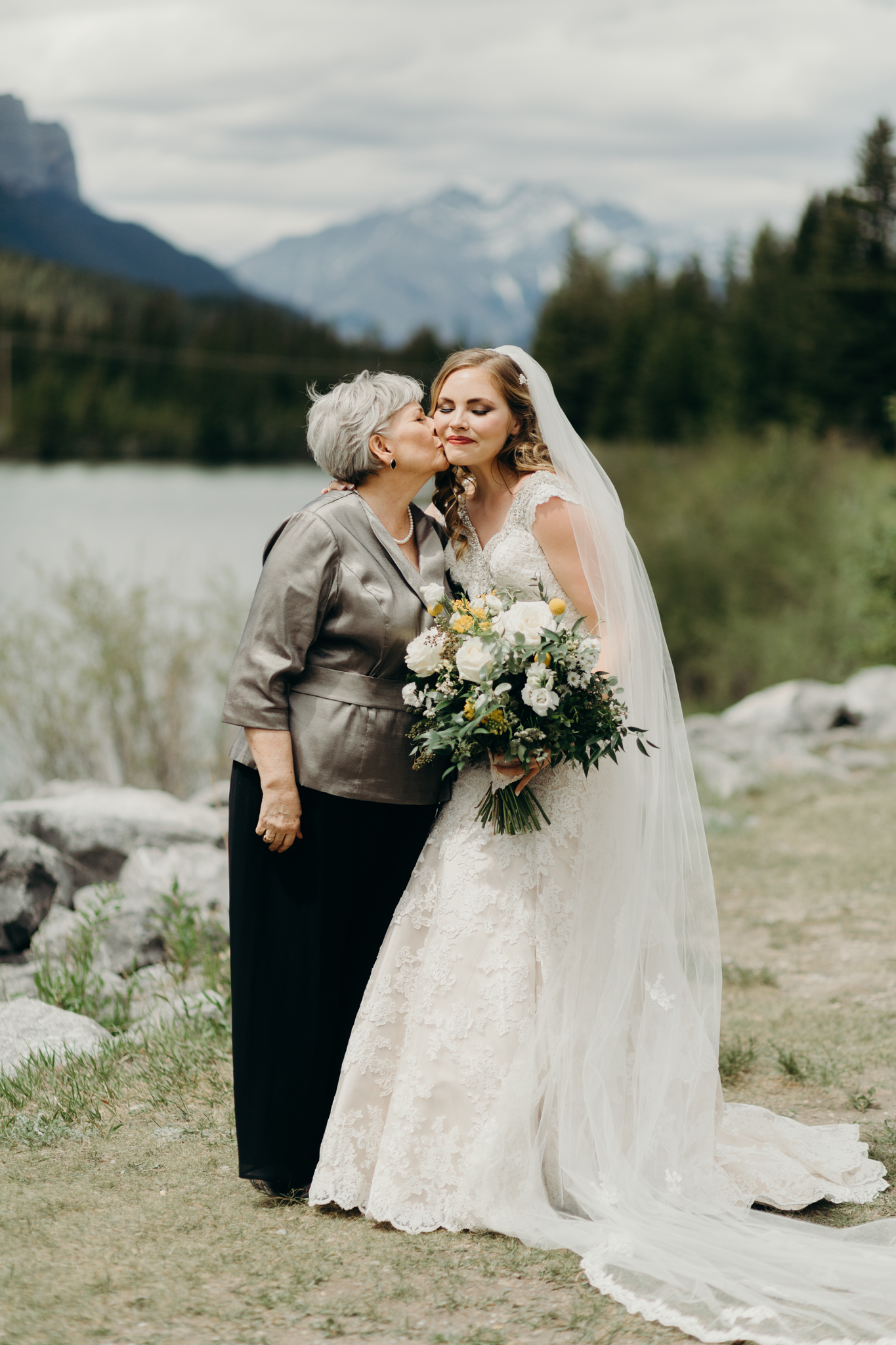 Bride and Mother of bride pose by river smiling destination wedding photographer MN